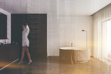 Fototapeta na wymiar Woman walking in white and gray bathroom