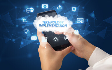 Female hand holding smartphone with TECHNOLOGY IMPLEMENTATION inscription, cloud technology concept