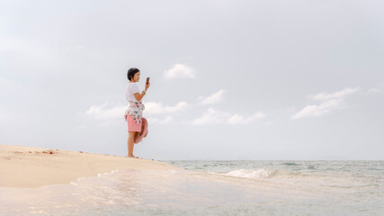 Fototapeta premium Woman standing on the phone on the beach, she felt calm and private.