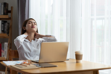 Young businesswoman is having pain in neck at work