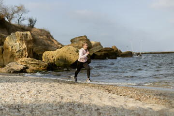 Fitness woman running on wild beach on bright sunny day