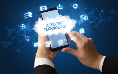 Female hand holding smartphone with ASSISTIVE TECHNOLOGY inscription, cloud technology concept