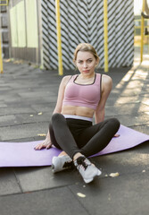 Fit woman resting on yoga mat at outdoor sports ground