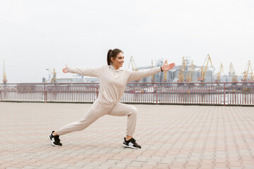 Fototapeta premium Healthy fit woman practicing yoga asana exercises on the background of an industrial city. Warrior 2 pose