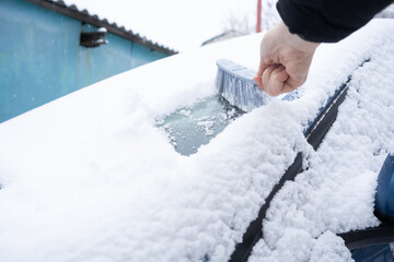 Clearing snow from the car windshield with car brush