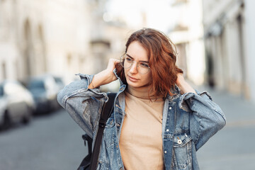 Stylish attractive woman in denim jacket on urban street