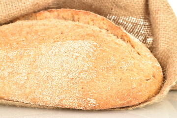 One fresh loaf without yeast with cereal with a jute bag, close-up.