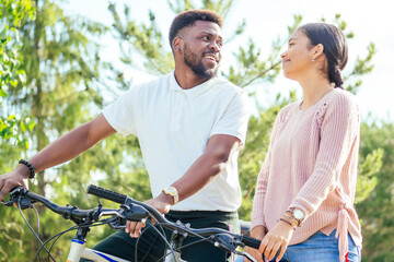 Laughing young couple riding bicycles in downtown
