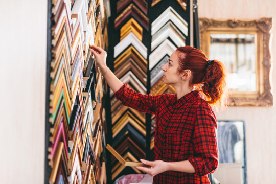 Woman shop assistant picking a wooden picture frame.