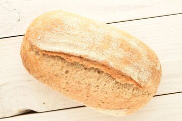 One fresh loaf without yeast with cereal with a jute napkin on a wooden table, close-up, top view.