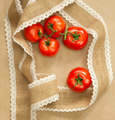 Red Tomatoes on brown craft paper background with natural colored burlap ribbon top view, copy space, Vegan, vegetarian,healthy food,vegetables concept