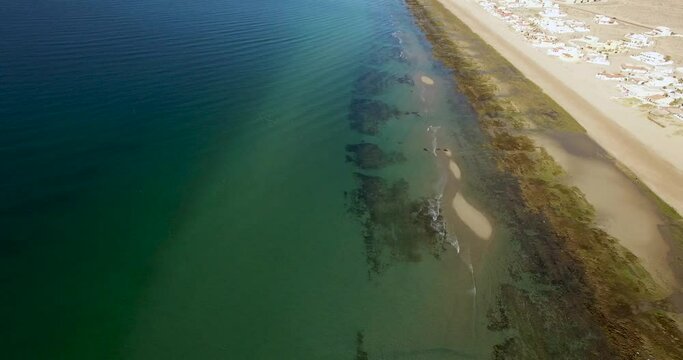 Tilt down on the shoreline of the andy beaches of the American enclave of Las Conchas, Rocky Point, Mexico.