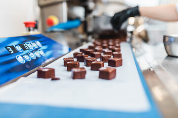 Professional confectioner making delicious chocolate sweets. Sweets production and industry concept.