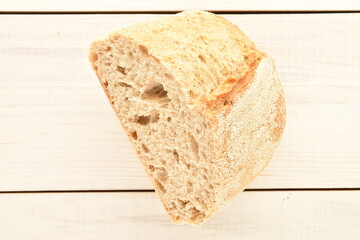 One half flavored loaf without yeast with bran cereal, close-up, on a wooden table.