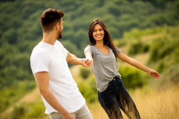 Happy young couple in love walking through grass field