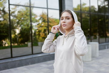 Portrait of a stylish runner woman in hood outdoors. Fitness concept