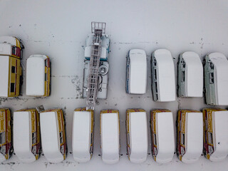 Snow-covered emergency special vehicles in the parking lot. Snowy day, blizzard. Aerial drone view.