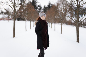 Happy young girl in winter clothes with snow on the road