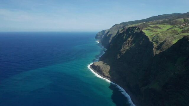 Stunning blue Atlantic Ocean meeting steep rocky cliffs of Madeira island