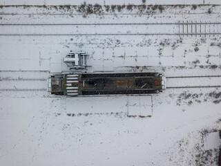 Diesel locomotive covered with snow. Snowy day, blizzard. Aerial drone top view.
