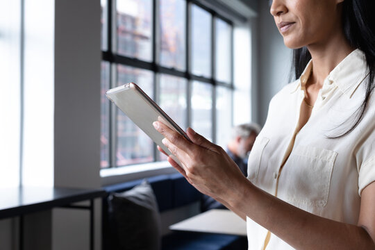 Mxed race businesswoman standing using digital tablet in modern office