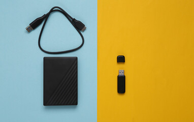 USB flash drive and external hard drive on a yellow blue background. Top view