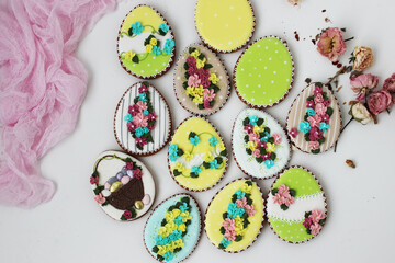 Easter colored gingerbread in the shape of an egg with a rabbit and flowers drawn on them.