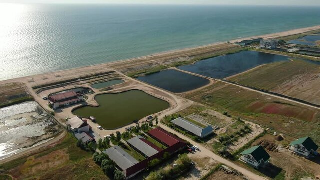 Fish ponds near the sea or ocean in an aquaculture farm - farming enclosures with fresh water where trout, carp or salmon is raised commercially for food. Aerial view of the tanks. 4k video