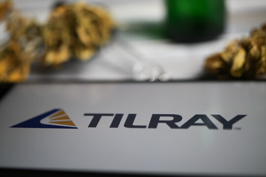 Viersen, Germany - January 9. 2021: Closeup of mobile phone screen with logo lettering of cannabinoid company Tilray, blurred marijuana and pipette background