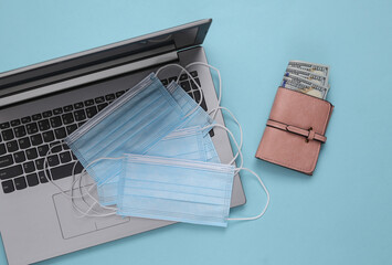 Laptop and medical masks, wallet on a blue background. Top view