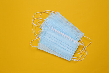 Medical facial masks on a yellow background. Top view
