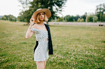 Elegant stylish blonde short hair girl in hat posing in the field