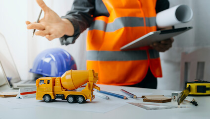 Fototapeta premium Two colleagues discussing data working and tablet, laptop with on on architectural project at construction site at desk in office