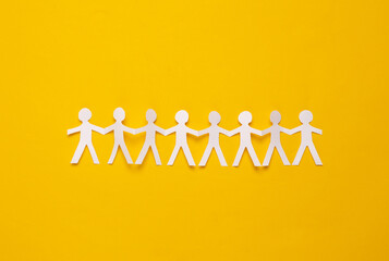 Cut paper human chain hold hands and show their unity on yellow background. Solidarity and peace