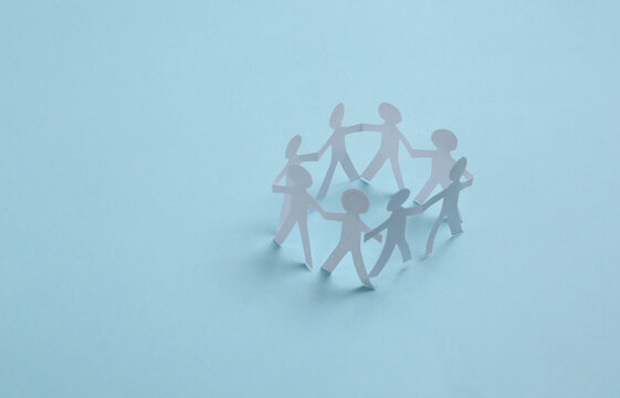 Cut paper human chain hold hands and show their unity on blue background. Solidarity and peace