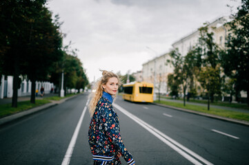 Beautiful stylish blonde model in colored suit posing in the street