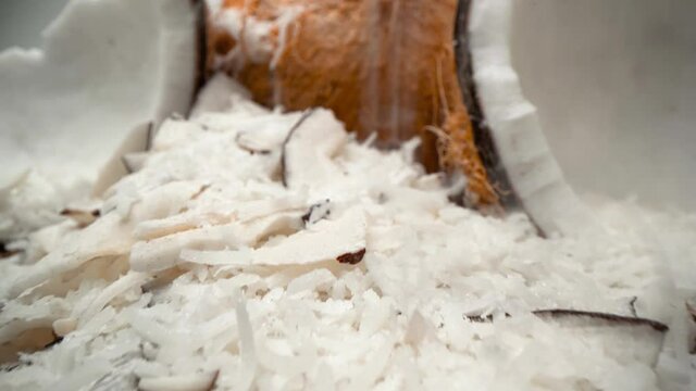 Coconuts and shredded coconut flakes close up falling into tower ingredient pull away 4k food product video