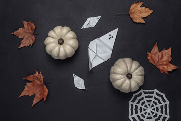 Halloween theme. Origami ghosts, pumpkins, fallen leaves on a black background. Top view