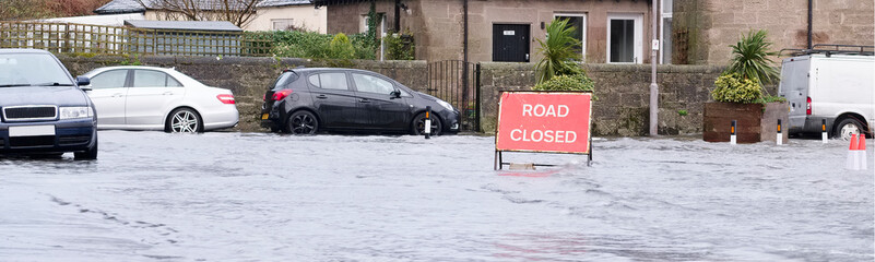 Road flood closed sign under deep water during bad extreme heavy rain storm weather