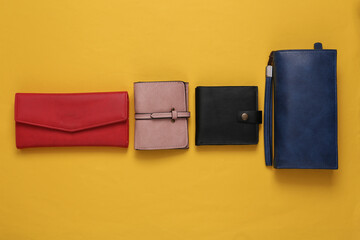 Different leather wallets on yellow background. Top view