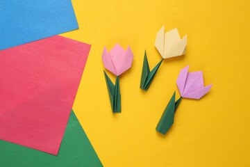 Origami bright tulip flowers on colored paper background.