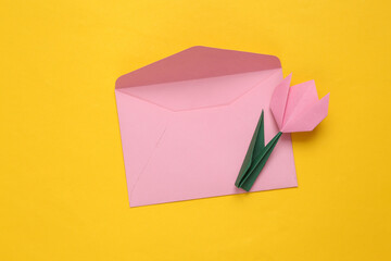 Mother's day concept. .Origami bright tulip flower and envelope on yellow paper background.