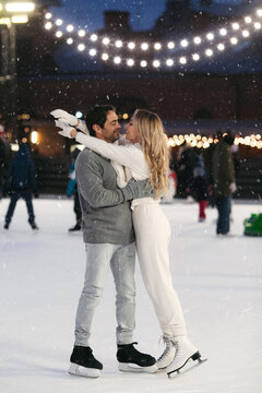 Happy couple of lovers having fun, hugging at ice skating rink outdoor. St. Valentines Day, Winter leisure, New Year holidays concept.