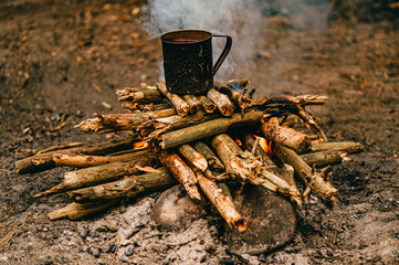 Tea in metal mug heats up on bonfire