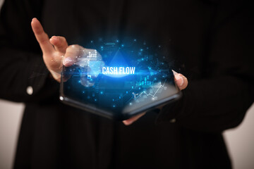 Businessman holding a foldable smartphone with CASH FLOW inscription, business concept