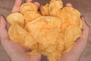 Hands are holding potato chips. Junk food made from cholesterol. Salty and crispy.