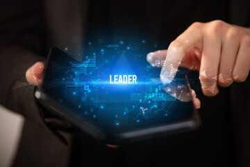 Businessman holding a foldable smartphone with LEADER inscription, business concept