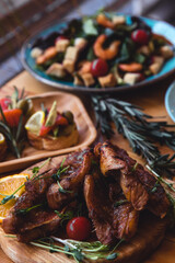 Fish Meat on a Black Tray with Herbs and Spices on Top of a Rustic Wooden Table with Organic Veggies. Captured in High Angle View.