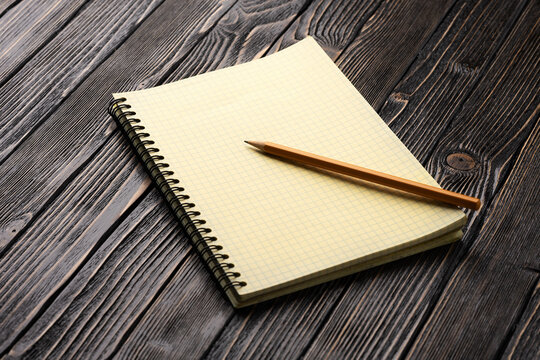 yellow notepad and pencil on brown wooden table