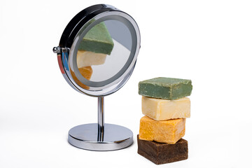 variety of Handmade colored soap and mirror on a white background
